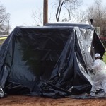 Laborers use long poles to maneuver the plastic sheeting into place.